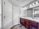 Bathroom with dual sinks, cherry cabinet, and wood-look floors at 284 Talladega Ln, Polk City, FL 33868