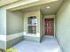 View of a front porch that has a large brown front door and white trimmed window at 284 Talladega Ln, Polk City, FL 33868