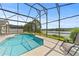 Sparkling screened-in pool and patio overlooking a serene lake, creating a private oasis at 2889 Blooming Alamanda Loop, Kissimmee, FL 34747