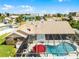 An aerial view of the house featuring a screened-in pool, an umbrella, and surrounding greenery at 30 Capistrano Dr, Ormond Beach, FL 32176