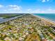 Expansive aerial view showcasing a coastal neighborhood with a mix of residential homes and beachside resorts at 30 Capistrano Dr, Ormond Beach, FL 32176
