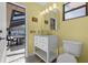 Yellow half-bath with a white vanity, toilet, and backyard view at 30 Capistrano Dr, Ormond Beach, FL 32176