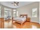 Comfortable bedroom featuring a wooden bed frame, hardwood floors, and natural light from multiple windows at 339 Hammock Dunes Pl, Orlando, FL 32828