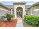 Inviting front entrance with double doors, arched transom window, and lush landscaping at 339 Hammock Dunes Pl, Orlando, FL 32828