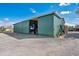 Exterior side view of an open green metal outbuilding with equipment and accessories visible inside at 4640 Hickory Tree Rd, St Cloud, FL 34772