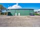 Exterior of a green metal outbuilding or barn with multiple doors and a covered side structure at 4640 Hickory Tree Rd, St Cloud, FL 34772