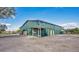 Large, green metal barn with an overhanging porch area and ample parking, perfect for various uses at 4640 Hickory Tree Rd, St Cloud, FL 34772