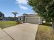 Charming single-story home with a well-maintained lawn, a palm tree, and a two-car garage at 4841 Hickory Stream Ln, Mulberry, FL 33860