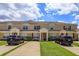 A charming townhome exterior boasting well-maintained landscaping, and a welcoming facade under a bright, cloudy sky at 8110 Princess Palm Ln, Kissimmee, FL 34747