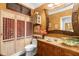 Bathroom with red and gold accents has a custom vanity, granite top and unique sink at 9049 Saint Andrews Way, Mount Dora, FL 32757