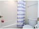 Clean bathroom featuring a white tiled tub-shower, a purple and white shower curtain, and a white toilet at 10038 Verse Aly, Winter Garden, FL 34787