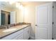 Bathroom with dual sinks, neutral countertops, white cabinets, a large mirror, and a closed door at 10038 Verse Aly, Winter Garden, FL 34787