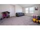 Spacious bedroom with a gray sofa, neutral carpet, a dollhouse, and natural light from two windows at 10038 Verse Aly, Winter Garden, FL 34787