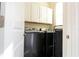 Modern laundry room with a black front loading washer and dryer and white cabinets for storage at 10038 Verse Aly, Winter Garden, FL 34787
