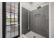 Modern bathroom with gray tiled shower, gold fixtures, a glass door, and an exterior view through windowed door at 11019 Kentmere Ct, Windermere, FL 34786