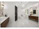 Bright bathroom featuring white marble floors, dual sinks, a modern tub, and decorative lighting fixtures at 11019 Kentmere Ct, Windermere, FL 34786