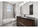 Modern bathroom featuring a marble tile shower and tub, and a dark wood vanity with a black countertop at 11019 Kentmere Ct, Windermere, FL 34786