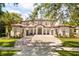 Elegant two-story home features a red tile roof, large brick driveway, and manicured landscaping at 11019 Kentmere Ct, Windermere, FL 34786