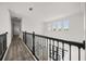Upstairs hallway with hardwood floors, black metal railing, and bright windows at 11019 Kentmere Ct, Windermere, FL 34786