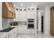 Modern white kitchen featuring stainless steel appliances, marble backsplash, and custom hood at 11019 Kentmere Ct, Windermere, FL 34786