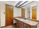 Bathroom featuring a long countertop with sink, wood cabinets, and a large mirror and two doors at 11632 Lake Willis Dr, Orlando, FL 32821
