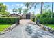 Gated driveway leading to home and large metal building with landscaping at 11632 Lake Willis Dr, Orlando, FL 32821
