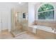 Bright bathroom showcasing a glass-enclosed shower with stone accents and a soaking tub by an arched window at 13124 Filly Ct, Windermere, FL 34786
