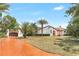 Stunning exterior view of Spanish-style home featuring a terracotta roof, palm trees, and a brick driveway at 13124 Filly Ct, Windermere, FL 34786