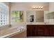 Bright bathroom with double sink vanity, soaking tub, framed mirror and decorative light fixture at 13609 Riggs Way, Windermere, FL 34786