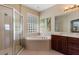 Bright bathroom featuring glass shower, soaking tub, window, and vanity with cabinet storage at 13609 Riggs Way, Windermere, FL 34786