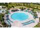 Stunning aerial view of a large, circular community pool surrounded by lounge chairs and tropical landscaping at 1425 Thunderbird Rd, Davenport, FL 33896