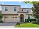 Inviting two-story home features an arched entryway, neat landscaping, and a convenient two-car garage at 1425 Thunderbird Rd, Davenport, FL 33896