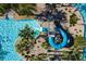 Aerial shot of a blue pool slide and splash area, surrounded by lush landscaping and crystal-clear water at 1425 Thunderbird Rd, Davenport, FL 33896
