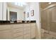 Well-lit bathroom features a double vanity with dark countertops and a glass-enclosed shower at 1663 Lima Ave, Kissimmee, FL 34747