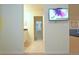 Hallway view showcasing neutral walls, tile flooring, a TV, and a glimpse into a bedroom at 1663 Lima Ave, Kissimmee, FL 34747