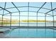 Screened-in pool with lake view and a hot tub surrounded by brick pavers, perfect for relaxation at 1663 Lima Ave, Kissimmee, FL 34747