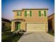 Charming two-story home with a large driveway, a two-car garage, a green front door, and landscaping at 1800 Post Oak Dr, Davenport, FL 33837
