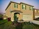Two-story home featuring tan siding, green shutters, and a well-maintained front yard at 1800 Post Oak Dr, Davenport, FL 33837