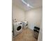 Well-equipped laundry room with modern, white washer and dryer units and tiled flooring for easy cleaning at 1800 Post Oak Dr, Davenport, FL 33837