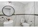 This powder room has marble walls, a pedestal sink, round mirror, and modern fixtures at 203 E Greentree Ln, Lake Mary, FL 32746