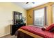 Cozy bedroom with yellow walls, a dark wood dresser, and a comfortable bed adorned with patterned bedding at 2302 Butterfly Palm Way # 105, Kissimmee, FL 34747