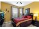 Comfortable bedroom featuring a cozy bed, warm yellow walls, and a dark wood nightstand with an elegant lamp at 2302 Butterfly Palm Way # 105, Kissimmee, FL 34747