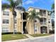 Inviting condo exterior with lush palm trees, easy stairway access, and well-manicured landscape at 2302 Butterfly Palm Way # 105, Kissimmee, FL 34747