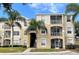 Inviting condo exterior boasts screened balconies and lush palm trees against a blue sky at 2302 Butterfly Palm Way # 105, Kissimmee, FL 34747