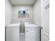Laundry room with washer and dryer units, wire rack shelving, and white walls at 2636 Grand Central Ave, Tavares, FL 32778