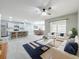 Bright living room with ceiling fan, light gray walls, open layout to kitchen and dining area, and gray wood-look tile floors at 2636 Grand Central Ave, Tavares, FL 32778