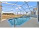 Screened-in pool surrounded by neutral-colored patio, clear skies and green outdoor scenery at 314 Lady Diana Dr, Davenport, FL 33837
