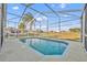 Screened-in pool surrounded by neutral-colored patio, clear skies and green outdoor scenery at 314 Lady Diana Dr, Davenport, FL 33837