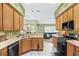 Bright kitchen with wood cabinets, black appliances, white tile floors and open access to the living room at 346 Hickory Springs Ct, Debary, FL 32713