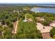 Aerial view of a large, fenced property featuring a home, additional buildings, mature trees and lake views at 36408 E Eldorado Lake Dr, Eustis, FL 32736